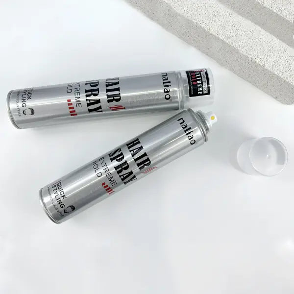Two cans of hair spray with visible labels on a white surface.