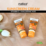 Two tubes of Naliao sunscreen cream with vitamin C and hyaluronic acid on a beige fabric background. maliao.pk